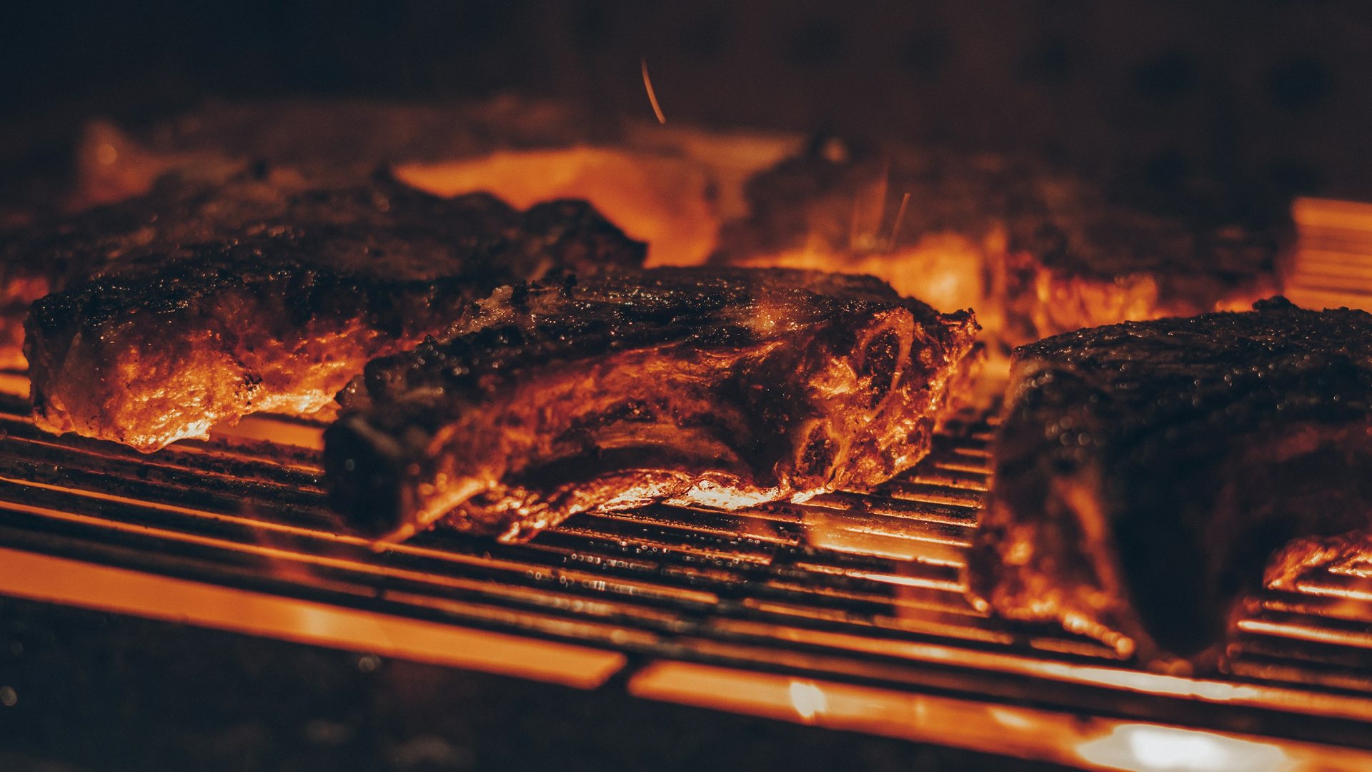Parrilla encendida con cortes de carne sobre brasas